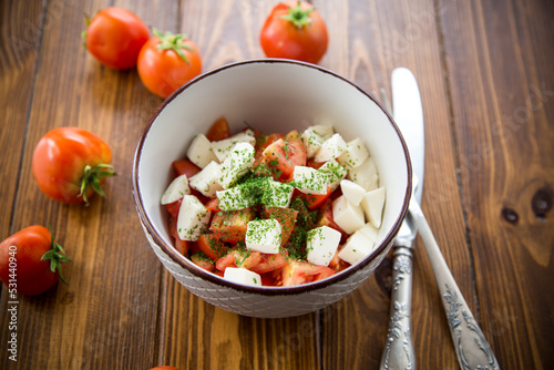 salad of fresh ripe tomatoes with mozzarella and spices in a bowl