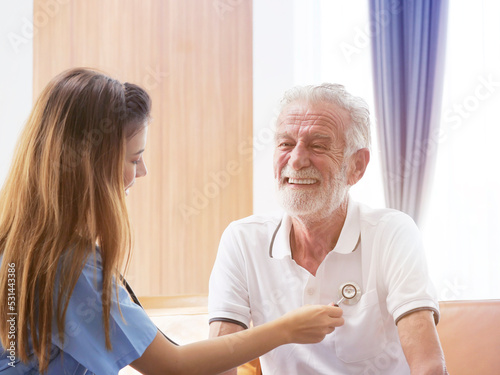Health visitor talking to a senior man during home visit , Female caregiver doctor supporting smiling older man