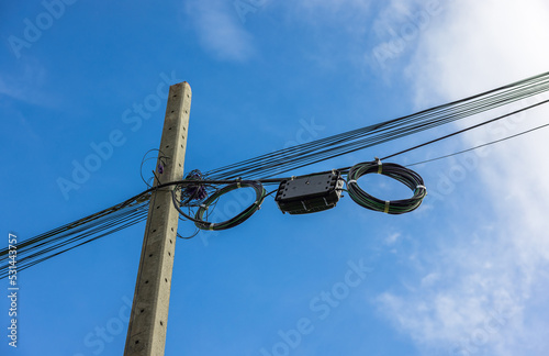 A roll of fiber-optic cables is suspended from a pole. High-speed internet communication optical fiber cable On a blue sky background with white copy space.