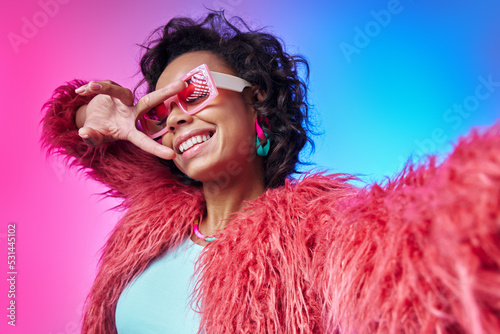 Playful African woman in trendy clothes making selfie and gesturing against colorful background © gstockstudio