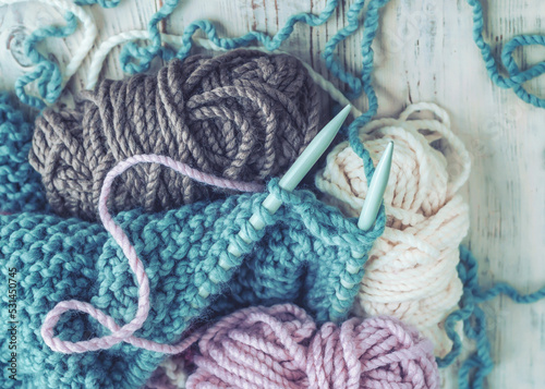 Skeins of thread and knitting needles on wooden background, selective focus.