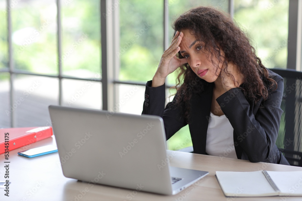 Mid adult businesswoman touching her head on table in office after bad news business failure or get fired and feeling discouraged, distraught and hopeless in modern office. Mid adult businesswoman touching her head on table in office after bad news business failure or get fired and feeling discouraged, distraught and hopeless in modern office.
