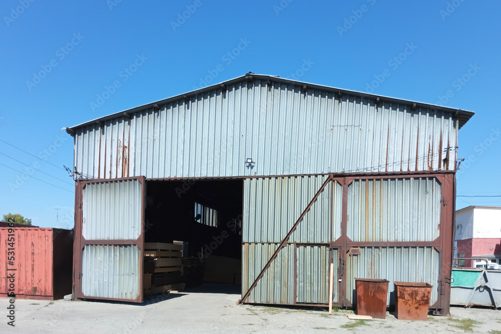 Industrial old metal hangar. Summer against the blue sky.