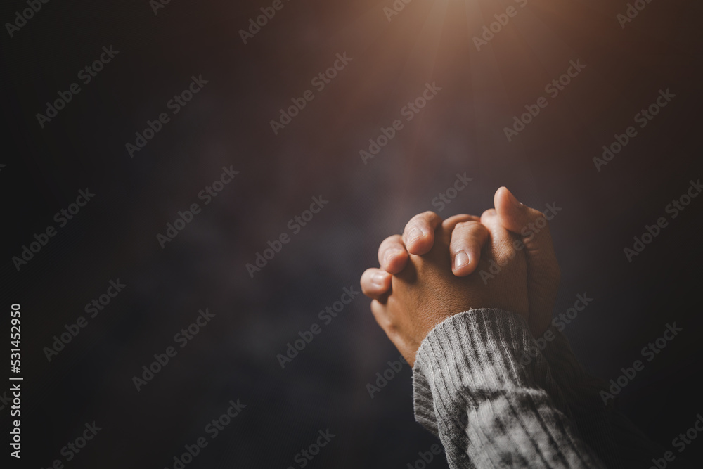 Prayer person hand in black background. Christian catholic woman are praying to god in dark at church. Girl believe and faith in jesus christ. Christ religion and christianity worship or pray concept. - obrazy, fototapety, plakaty 