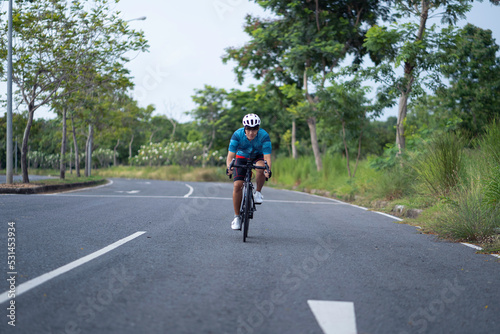 Asian man Cyclist Riding On Road Bike In City Park. © kokotewan