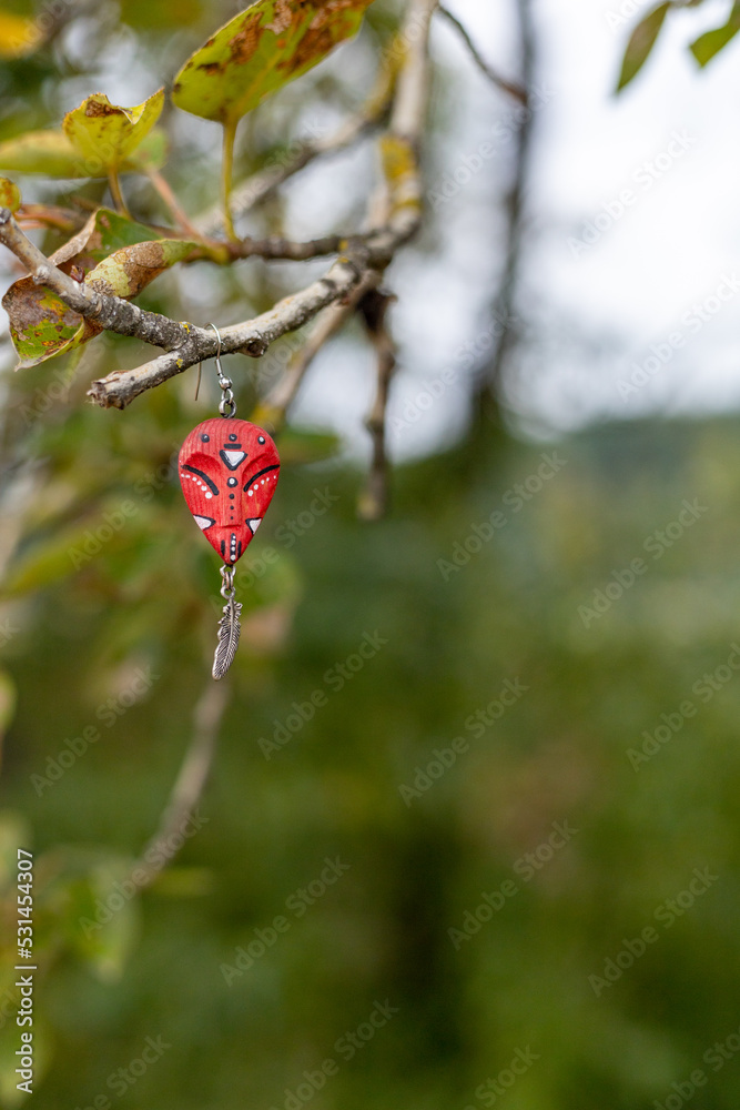 Obraz premium An earring in the form of an African mask hangs on a tree branch