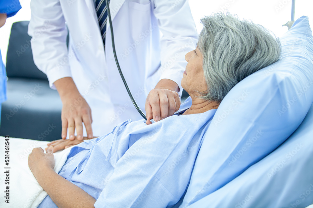 doctor visiting ward have woman patient and check her with stethoscope on bed. Woman patient lying on hospital bed while doctor giving her checkup. doctor visiting ward have woman patient and check her with stethoscope on bed. Woman patient lying on hospital bed while doctor giving her checkup.