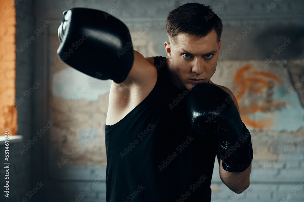 Handsome young man practicing in punching while standing in gym