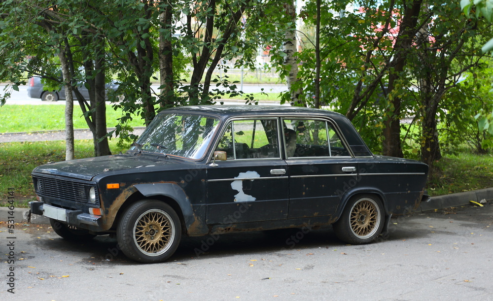 An old dark Soviet car in the courtyard of a residential building, Kollontai Street, St. Petersburg, Russia, September 2022