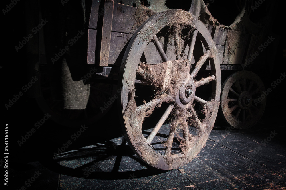 A wheel of the vintage wooden wagon on the dark background