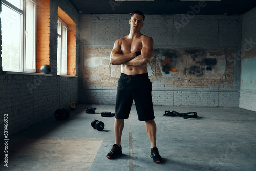 Full length of handsome muscular man keeping arms crossed while standing in gym