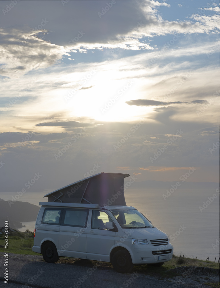 Fototapeta premium Camper standing on mountain at sunset in front of the ocean