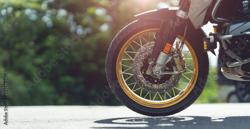 Part of a motorcycle wheel, tire, parked on a beautiful road. motorcycle in a sunny motorbike on the road riding.with sunset light. copyspace for your individual text.
