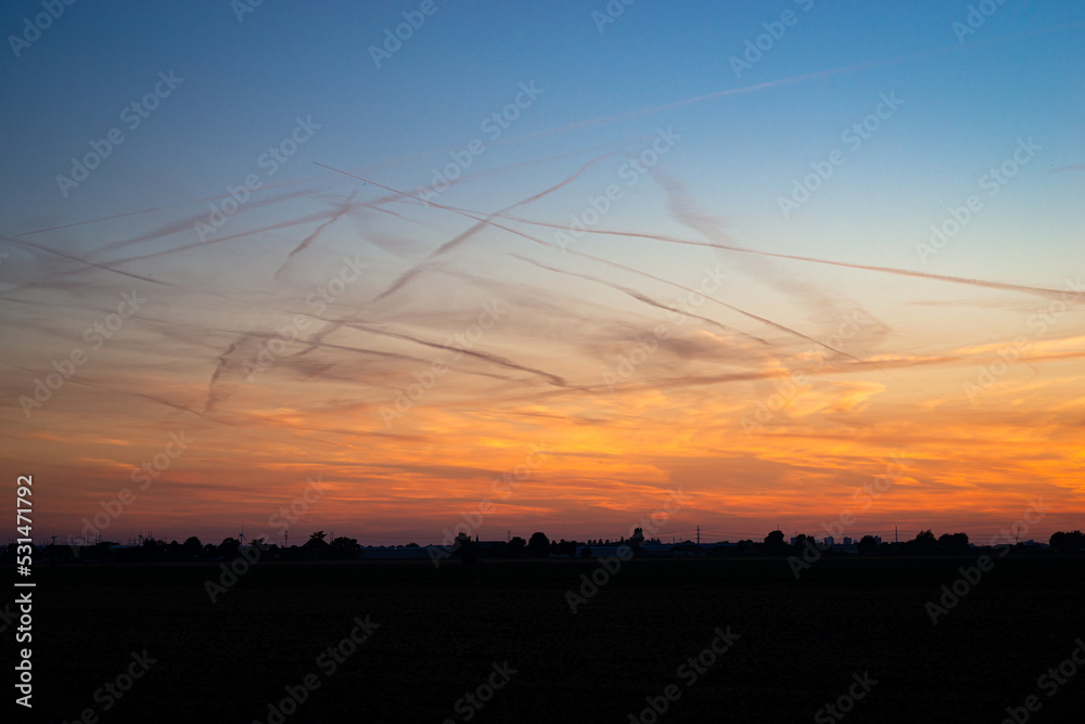 Many contrails in the evening sky, formed by the emission of water vapor from aircraft at high altitude Many contrails in the evening sky, formed by the emission of water vapor from aircraft at high altitude