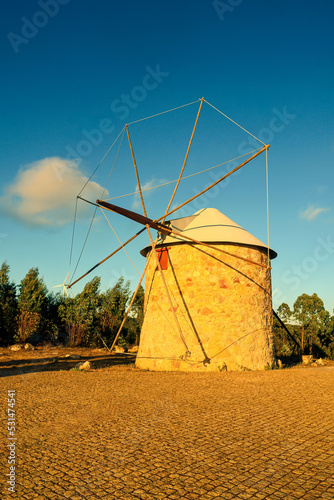 Old stone windmill in the rays of the sunset. Rural mountain landscape in retro style