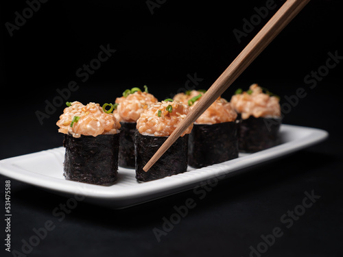 Take one sushi roll from black slate board using chopsticks