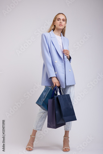 Wallpaper Mural High fashion photo of a beautiful elegant young woman in a pretty blue jacket, blazer, denim jeans, shopping bags posing over white, soft gray background. Studio Shot. Slim Figure, Blonde Torontodigital.ca