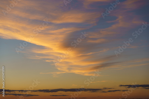 Beautiful sunset or dawn sky background with clouds of vibrant evening yellow orange colors and gradients.