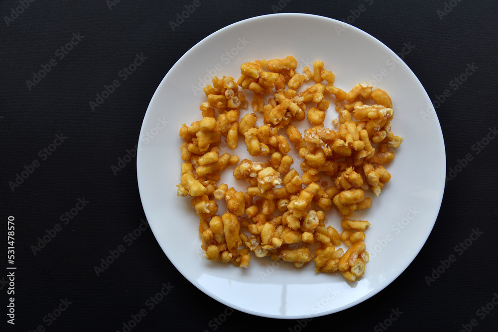 Sweet snack chuck-chuck in a package on a white plate. Honey snack made of dough close-up.