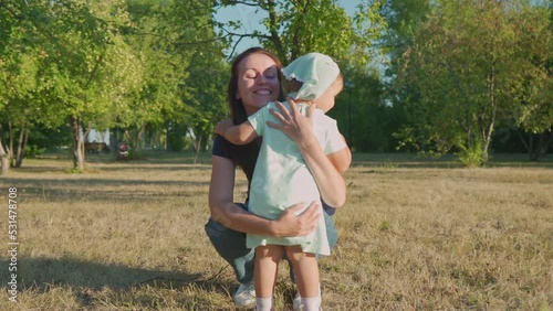 A little girl runs to her mom in the park and hugs her