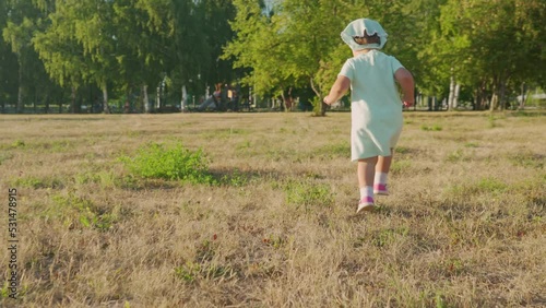 A little girl aged 2 years runs around the park
