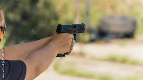 unrecognizable woman practicing aiming with a gun at the outdoor range. High quality photo
