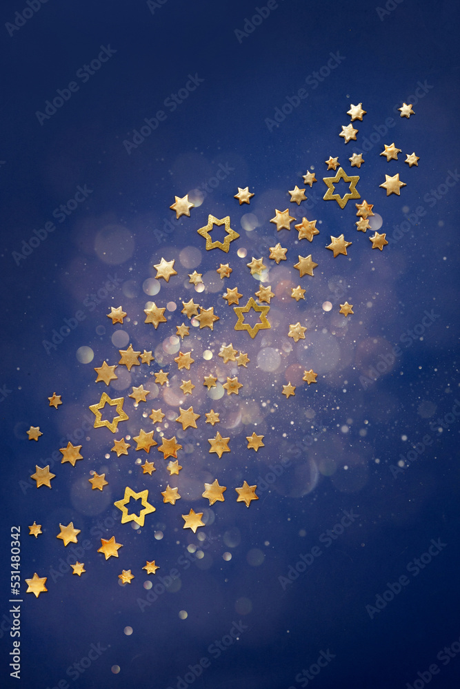 Golden Christmas stars on a defocused blue background with bokeh.