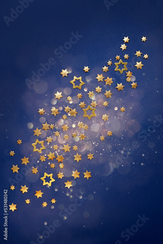 Golden Christmas stars on a defocused blue background with bokeh.