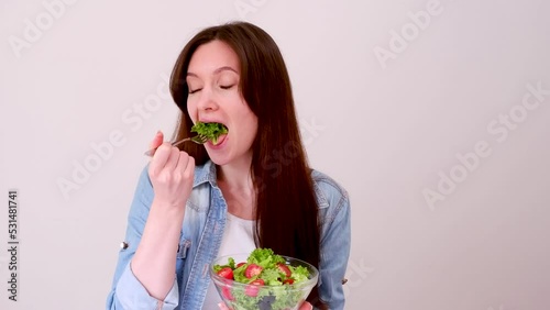 Beautiful young woman eats salad with lettuce, tomato and olives. Close-up 4k footage