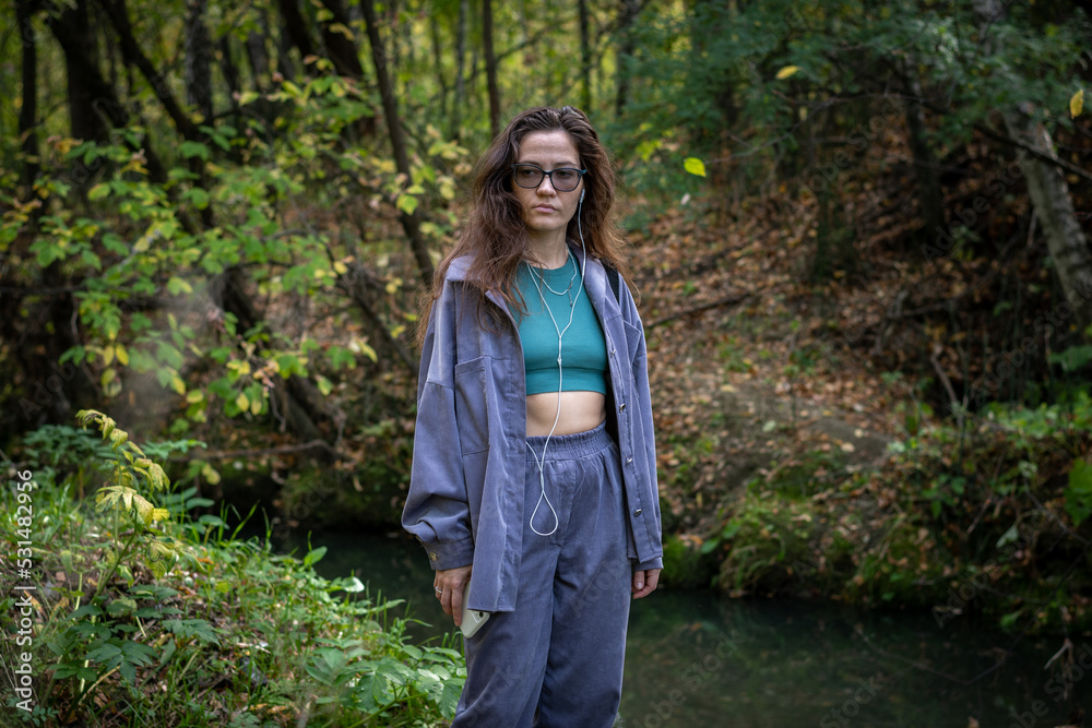 Portrait of romantic woman at fairy forest. A beautiful young girl with glasses is walking through the forest. Girl purple suit. Corduroy fabric Portrait of romantic woman at fairy forest. A beautiful young girl with glasses is walking through the forest. Girl purple suit. Corduroy fabric