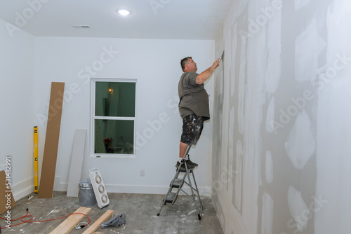 Фотография Worker the process trowels putty on drywall finishing putty with hand a spatula