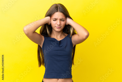 Little caucasian girl isolated on yellow background frustrated and covering ears