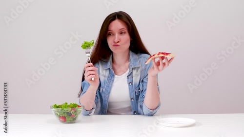 Young woman on a diet wants to eat pizza but makes a choice in favor of salad