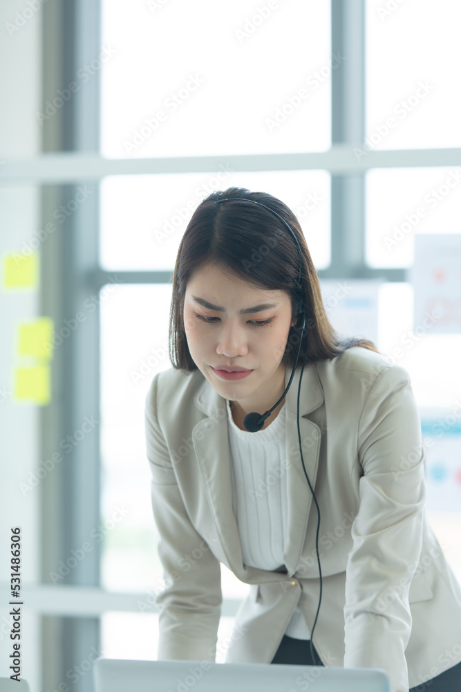 Young asian woman working at a call center Consulting about stock investment information with customers calling for advice with emotion of serious