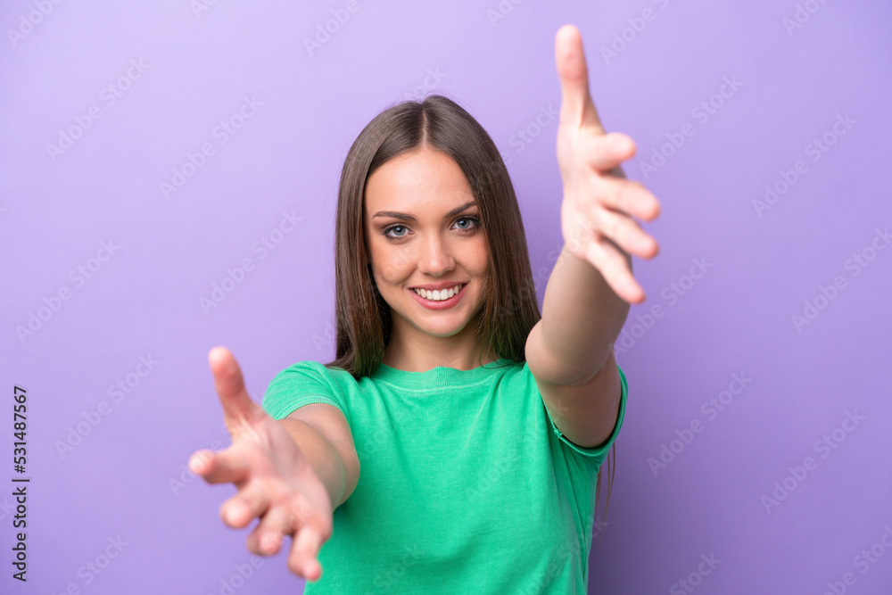 Young caucasian woman isolated on purple background presenting and inviting to come with hand Young caucasian woman isolated on purple background presenting and inviting to come with hand