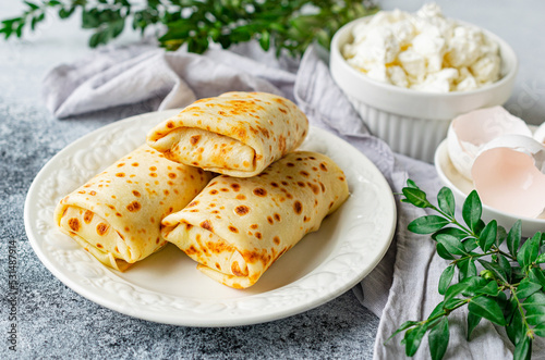 Pancakes stuffed with cottage cheese and herbs on a white plate