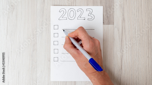 Canvas Print A woman's hand fills the checklist with a pen for the new year 2023