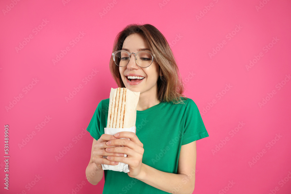 Emotional young woman with delicious shawarma on pink background Emotional young woman with delicious shawarma on pink background