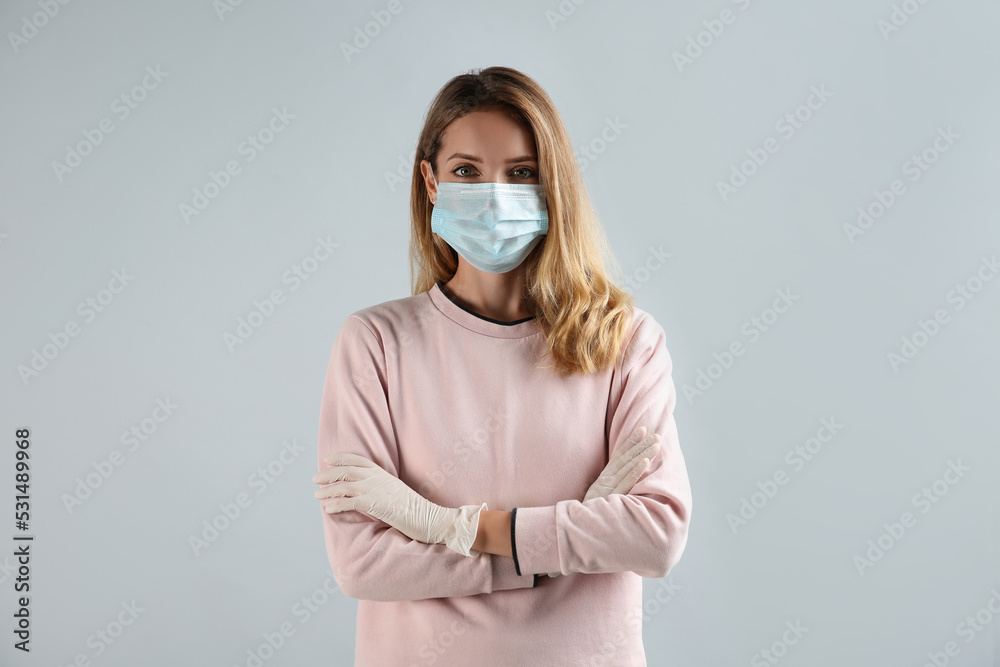 Young woman in medical gloves and protective mask on grey background Young woman in medical gloves and protective mask on grey background