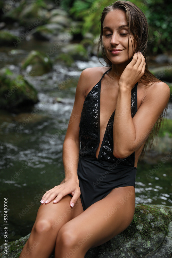 Beautiful young woman relaxing on rock near mountain river outdoors Beautiful young woman relaxing on rock near mountain river outdoors