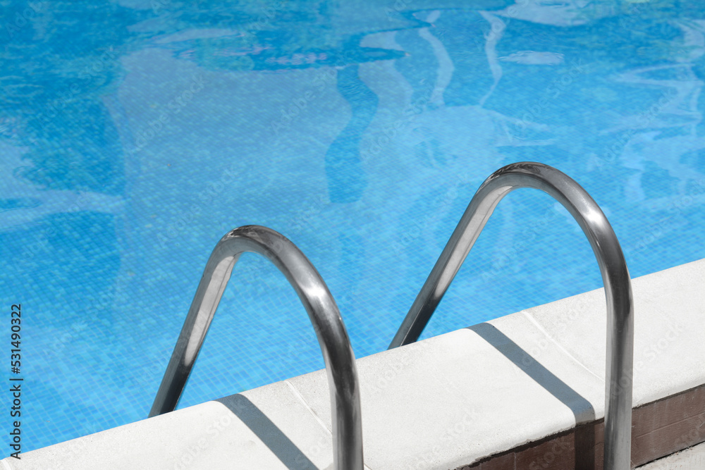 Swimming pool with metal ladder on sunny day Swimming pool with metal ladder on sunny day