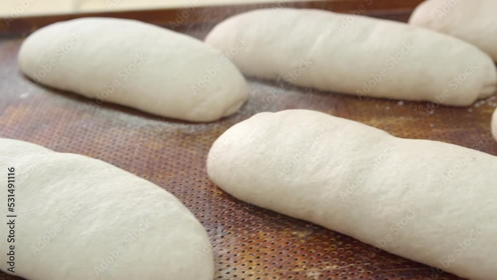Bakers sprinkle flour a lot of ready-to-bake breads that lie on the table Bakers sprinkle flour a lot of ready-to-bake breads that lie on the table