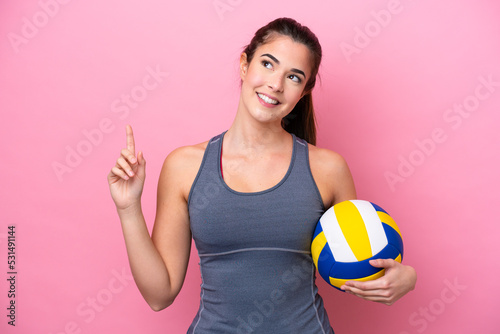 Young Brazilian woman playing volleyball isolated on pink background pointing up a great idea