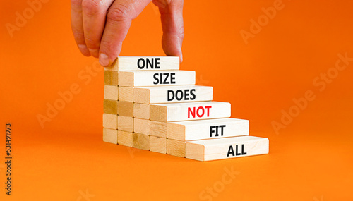 One size does not fit all symbol. Concept words One size does not fit all on wooden blocks. Businessman hand. Beautiful orange background. One size does not fit all business concept. Copy space. photo