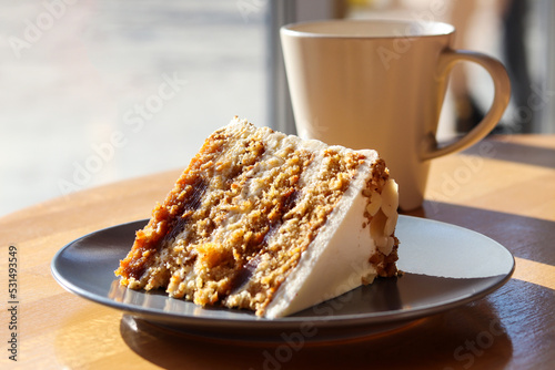 A piece of carrot cake on the table with a cup of coffee or tea close-up. Selective focus