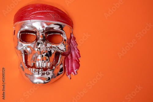 Fotografie, Obraz a silver skull with a red headband on a red background