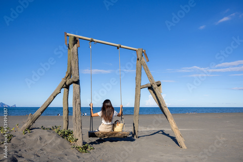 Woman play with swing on sand beach photo