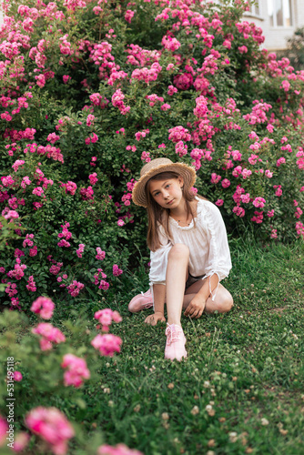 Summer stories of a little girl. White T-shirt. Straw hat. Pink roses.