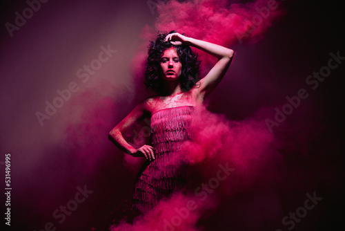 High fashion photo of a beautiful elegant young woman in flying pink dry paints. indian Holi paints. studio shooting