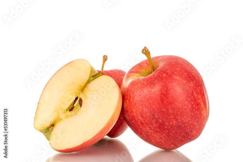 One half and two whole juicy red apples, macro, isolated on white background.